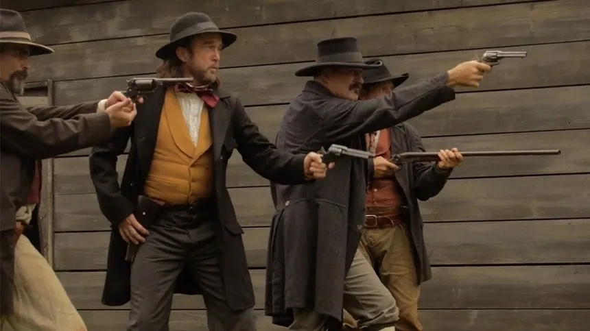 A group of men in black suits and hats holding guns.