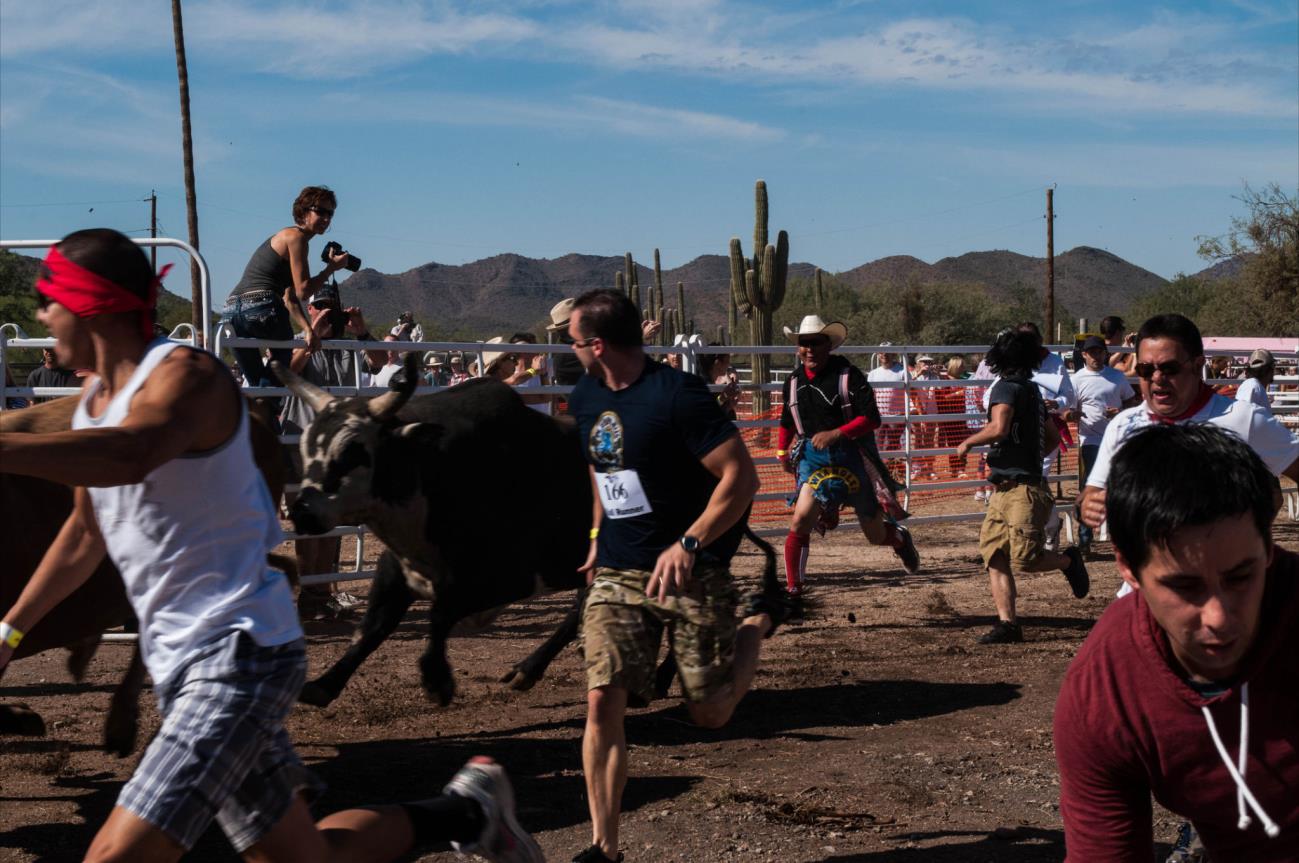 A man is running with a bull in the dirt.