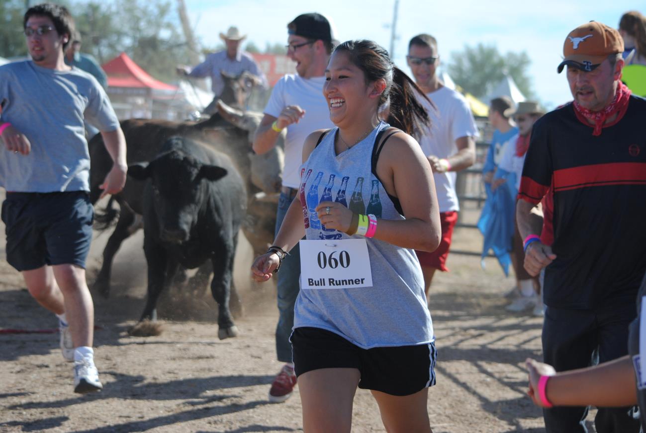 A woman running in the dirt with people around.