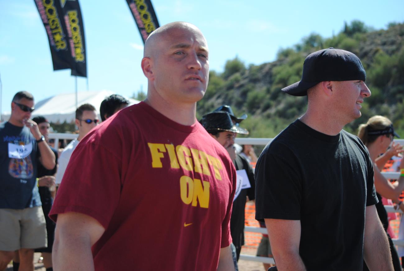 A man in red shirt standing next to another man.