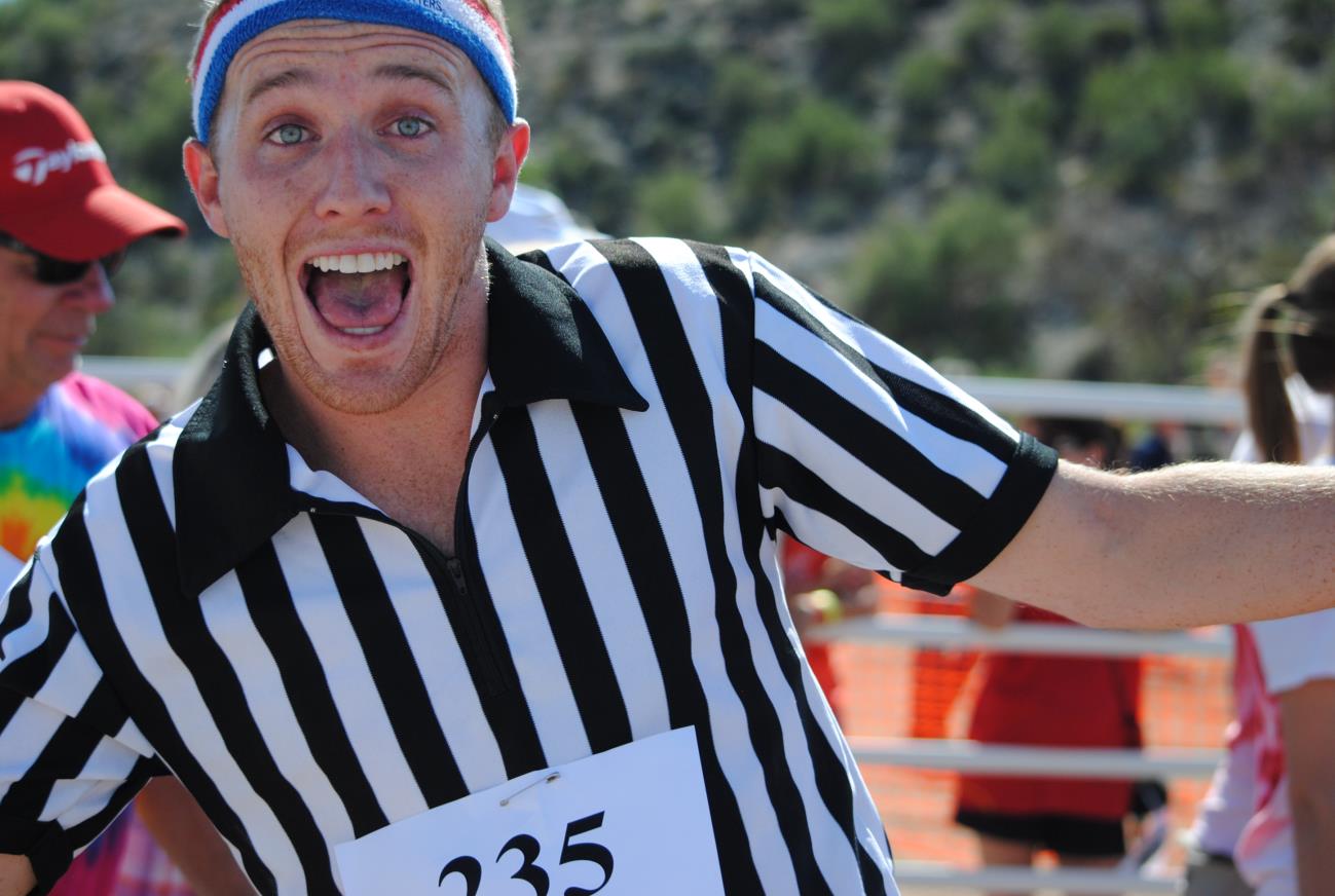 A man in a referee outfit is smiling for the camera.