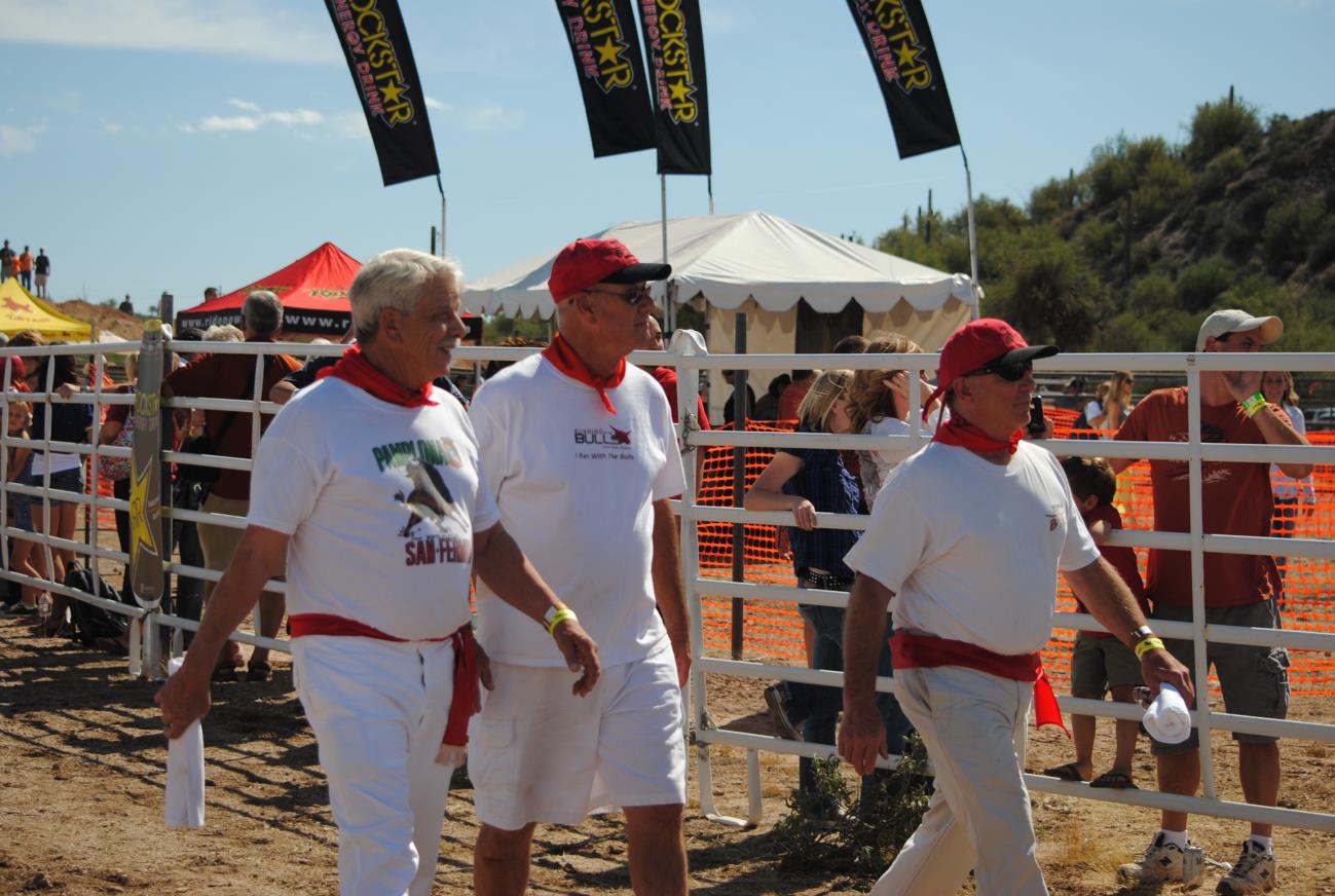 Three men in white shirts and red hats standing next to each other.