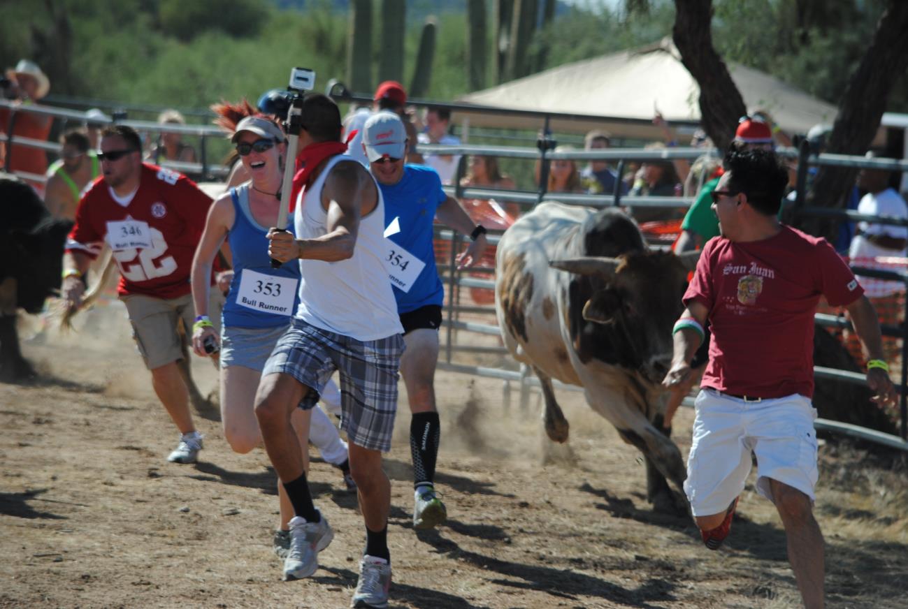 A group of people running around a bull.