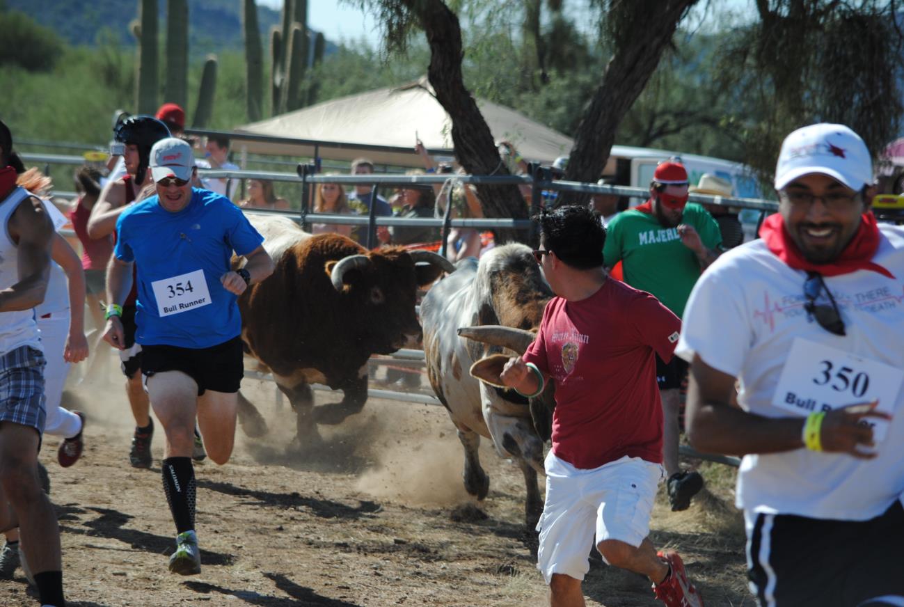 A group of people running around a bull.